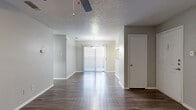 This single-story, 2-bedroom, 2-bathroom residence offers a functional and comfortable layout across a well-utilized footprint. The living room serves as the centerpiece of the home, showcasing a white brick fireplace flanked by built-in shelving, durable wood-look flooring, a ceiling fan, and a textured ceiling. A sliding glass door allows natural light to pour in, extending the feel of the space outward. The kitchen is efficiently designed with granite countertops, white cabinetry, stainless steel appliances including a refrigerator and electric range, and a built-in pantry closet offering generous storage. Both bedrooms feature plush wall-to-wall carpeting, ceiling fans, and access to closets — including a walk-in closet with built-in shelving. The primary bedroom is comfortably sized with a sliding door panel and its own ceiling fan. The bathrooms are clean and functional, each featuring a shower-tub combination with tiled surround and wood-look flooring. A connecting hallway ties the layout together seamlessly. Neutral gray walls and consistent finishes throughout create a cohesive, move-in ready atmosphere suited for a variety of lifestyles.