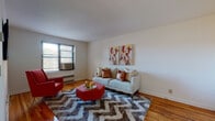 Located at 100 Hoyt St in Stamford, Connecticut, this single-floor residence offers a well-organized and comfortable layout with consistent design elements throughout. The living area is anchored by warm hardwood flooring and neutral white walls that create a bright, inviting atmosphere. Natural light filters in through windows fitted with blinds, complementing the open feel of the space. A wall-mounted flat-screen TV and ample room for seating make the living area well-suited for relaxing and entertaining.

The bedroom continues the hardwood flooring theme and features windows on multiple walls, allowing for generous natural light. The room provides a calm, restful environment with sufficient space for a full bedroom suite.

The kitchen is equipped with white cabinetry, dark laminate countertops, a gas range, built-in microwave, and tile flooring, offering a practical and clean cooking environment. The bathroom features full tile surround on the tub-shower combo, a white vanity with under-cabinet storage, and a mirrored medicine cabinet, presenting a clean and classic aesthetic.

The entryway offers a clear and open transition into the living space, highlighted by the same rich hardwood floors that flow throughout the unit. Overall, the residence presents a cohesive, functional, and well-maintained living environment in the heart of Stamford.