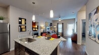 Located at 5072 Timberhill Dr in San Antonio, TX, this single-floor residence offers a thoughtfully designed open-concept layout with contemporary finishes throughout. The entryway makes a bold first impression, featuring striking large-scale artwork and a sculptural accent piece set against wood-look flooring. The kitchen is a standout centerpiece, equipped with dark cabinetry, stainless steel appliances including a refrigerator, electric range, and microwave, complemented by granite countertops and a kitchen island with pendant lighting overhead. A vibrant accent wall adds a lively pop of color to the kitchen area. The open living space flows seamlessly from the kitchen, offering room for comfortable seating, a ceiling fan, and windows that allow natural light to fill the area. The bedroom features a warm, richly colored accent wall, carpet flooring, and a window with ample natural light. The bathroom includes dark wood cabinetry, a granite-topped vanity, a large framed mirror, and wood-look flooring. Throughout the residence, a cohesive contemporary aesthetic is maintained with a mix of bold artwork, modern furnishings, and a neutral color palette accented with warm tones.