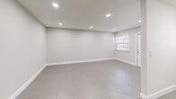 Located at 13890 NE 3rd Ct in North Miami, FL, this one-bedroom, two-bathroom unit offers a clean, modern layout designed for comfortable everyday living. Large-format neutral tile flooring runs consistently throughout the space, lending a cohesive and easy-to-maintain aesthetic.

The kitchen is well-appointed with crisp white cabinetry, a mosaic tile backsplash, recessed lighting, and full-size appliances including a refrigerator and range. The open, light-filled living area features recessed ceiling lights and a window that brings in natural light.

The spacious primary bedroom comfortably accommodates a full furniture arrangement and is equipped with a ceiling fan with integrated lighting, a wide window overlooking lush greenery, and two sets of louvered bifold closet doors providing ample storage.

The two bathrooms are finished in a clean, modern style. One features a floating white vanity with a white quartz countertop, an LED-backlit mirror, and direct hallway access to the kitchen. The second bathroom includes a full tub-shower combination surrounded by classic white subway tile and a privacy window.

A connecting hallway ties all rooms together efficiently, creating a practical and well-organized floor plan ideal for single occupants or couples in the heart of North Miami.