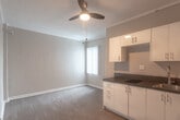 Located at 5640 Santa Monica Blvd in the heart of Los Angeles, CA, this single-floor unit offers a practical and efficiently designed living space. The open layout seamlessly connects the kitchen and living area, creating a cohesive and functional environment.

The kitchen is outfitted with white cabinetry — both upper and lower — providing ample storage, complemented by dark countertops that offer a clean contrast. A built-in electric cooktop, stainless steel sink, and a refrigerator complete the cooking space. Natural light filters in through a window dressed with vertical blinds, brightening the adjacent living area.

The living space features hardwood-style laminate flooring that runs throughout the unit, neutral-toned walls, and crown molding that adds a subtle architectural detail. A ceiling fan is present, contributing to overall comfort. The open, unfurnished layout offers flexibility for a variety of arrangements.

The bathroom is well-appointed with a pedestal-style vanity, a framed mirror, a walk-in shower, and a chrome light fixture above — all finished in a clean, all-white palette that enhances the sense of brightness. The overall ambiance of the unit is clean, neutral, and move-in ready, making it a straightforward and functional space in a central Los Angeles location.