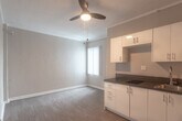Located at 5640 Santa Monica Blvd in the heart of Los Angeles, CA, this single-floor unit offers a practical and efficiently designed living space. The open layout seamlessly connects the kitchen and living area, creating a cohesive and functional environment.

The kitchen is outfitted with white cabinetry — both upper and lower — providing ample storage, complemented by dark countertops that offer a clean contrast. A built-in electric cooktop, stainless steel sink, and a refrigerator complete the cooking space. Natural light filters in through a window dressed with vertical blinds, brightening the adjacent living area.

The living space features hardwood-style laminate flooring that runs throughout the unit, neutral-toned walls, and crown molding that adds a subtle architectural detail. A ceiling fan is present, contributing to overall comfort. The open, unfurnished layout offers flexibility for a variety of arrangements.

The bathroom is well-appointed with a pedestal-style vanity, a framed mirror, a walk-in shower, and a chrome light fixture above — all finished in a clean, all-white palette that enhances the sense of brightness. The overall ambiance of the unit is clean, neutral, and move-in ready, making it a straightforward and functional space in a central Los Angeles location.