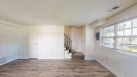 Located at 736 West Kingsway in Middle River, Maryland, this two-story home offers three bedrooms, one bathroom, and a practical layout spread evenly across two floors. The interior presents a clean, updated aesthetic throughout, with light-toned luxury vinyl plank flooring running consistently across the main and upper levels.

The main floor welcomes you through a bright front entry door flanked by windows that draw in natural light, opening into a spacious living room. A carpeted staircase with a sleek black metal railing leads to the upper level. The galley-style kitchen is a standout feature, finished with rich dark cabinetry, granite-look countertops, a stainless steel sink, and white appliances including a gas range, dishwasher, and refrigerator. A window above the counter adds natural light to the cooking space.

Upstairs, three bedrooms offer comfortable accommodations, including a primary bedroom of generous size. The bedrooms are bright and airy, with windows providing pleasant outdoor views. A notable feature of the upper level is the impressive closet storage — three side-by-side closets provide exceptional organization space. The full bathroom includes a tiled soaking tub/shower combination and a natural light window. A dedicated laundry area and hallway complete the upper floor layout.
