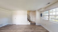 Located at 736 West Kingsway in Middle River, Maryland, this two-story home offers three bedrooms, one bathroom, and a practical layout spread evenly across two floors. The interior presents a clean, updated aesthetic throughout, with light-toned luxury vinyl plank flooring running consistently across the main and upper levels.

The main floor welcomes you through a bright front entry door flanked by windows that draw in natural light, opening into a spacious living room. A carpeted staircase with a sleek black metal railing leads to the upper level. The galley-style kitchen is a standout feature, finished with rich dark cabinetry, granite-look countertops, a stainless steel sink, and white appliances including a gas range, dishwasher, and refrigerator. A window above the counter adds natural light to the cooking space.

Upstairs, three bedrooms offer comfortable accommodations, including a primary bedroom of generous size. The bedrooms are bright and airy, with windows providing pleasant outdoor views. A notable feature of the upper level is the impressive closet storage — three side-by-side closets provide exceptional organization space. The full bathroom includes a tiled soaking tub/shower combination and a natural light window. A dedicated laundry area and hallway complete the upper floor layout.