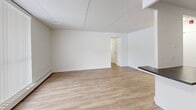 Located at 1001 Talwood Dr in Peterborough, Ontario, this 2-bedroom, 2-bathroom unit offers a clean, modern aesthetic throughout its thoughtfully designed single-floor layout. Light wood vinyl flooring flows seamlessly through the living spaces, complemented by crisp white walls and consistent flush-mount lighting.

The kitchen is a standout feature, showcasing white shaker-style cabinetry, a white subway tile backsplash, dark countertops, and a full suite of stainless steel appliances including a range, over-the-range microwave, dishwasher, and refrigerator. A peninsula counter connects the kitchen to the combined dining and living area, which benefits from a large floor-to-ceiling window dressed with vertical blinds, flooding the space with natural light.

Both bedrooms are well-sized, with the generously proportioned primary bedroom offering ample space. Each bedroom features light wood flooring, white walls, and baseboard heating. One bedroom includes dual windows with blinds, providing additional natural light.

The two bathrooms are finished with modern fixtures. One features a dark wood-toned vanity with a stone-look countertop and chrome hardware, while the other includes a bathtub/shower combination clad in classic white subway tile. A hallway with dedicated closet space completes the unit's practical layout.