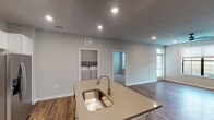 This single-story, two-bedroom, two-bathroom unit in Conroe, Texas offers a thoughtfully designed open-concept layout finished in a clean, contemporary aesthetic. Neutral gray walls, recessed lighting, and rich wood-style flooring run throughout the main living areas, creating a cohesive and inviting atmosphere.

The kitchen serves as the heart of the home, anchored by a central island with an undermount sink and taupe countertops. White shaker-style cabinetry extends to the ceiling, providing generous storage, while a light glass tile backsplash adds a subtle decorative touch. Stainless steel appliances, including a French door refrigerator, electric range, and built-in microwave, complete the space.

The open living area is bright and spacious, benefiting from natural light through multiple windows fitted with blinds and a ceiling fan overhead. Both bedrooms feature plush carpet and windows that bring in additional natural light.

Each bathroom is well-appointed with white shaker vanity cabinetry, taupe countertops, and tiled tub-shower combinations. A dedicated laundry closet with a full-size washer and dryer adds everyday convenience, rounding out this well-equipped and move-in-ready residence.