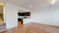 Located at 1904 East Palomar Street in Chula Vista, CA, this two-story home offers three bedrooms and three bathrooms across two well-proportioned floors. The main level features a welcoming entrance that leads into an open-concept living room and kitchen. The kitchen is thoughtfully appointed with rich dark wood cabinetry reaching to the ceiling, granite countertops, stainless steel appliances including a French door refrigerator, gas range, and microwave, along with a peninsula that provides additional counter space. Warm hardwood-style flooring flows throughout the main level, complementing the clean white walls and recessed lighting. A carpeted staircase connects the two floors, leading up to the bedroom level. The upper floor houses three carpeted bedrooms, each offering a bright and neutral environment. The bedrooms feature windows with blinds that allow natural light and views of the surrounding greenery. A hallway with closet storage provides practical organization. The three bathrooms are finished with tile flooring, white vanities, and tub-shower combinations. A notable feature of the home is a door on the upper level that opens to a small balcony overlooking the outdoors. The overall design is clean, modern, and functional, making this Chula Vista home a well-structured and comfortable space.