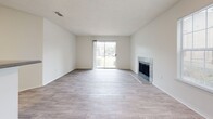 Located at 2945 Layfair in Flowood, Mississippi, this single-story home offers a well-organized layout with a bright, open feel throughout. The living room is a standout space, featuring light wood-style flooring, a tile-surround fireplace, and a sliding glass door that invites natural light and provides outdoor access. The open-concept design connects the living area seamlessly to the kitchen, which is outfitted with crisp white cabinetry, light wood-style flooring, stainless steel appliances including a range, dishwasher, and refrigerator, as well as a peninsula that defines the space without closing it off. A separate dining or living area is also present, featuring similar flooring and a large window that fills the room with natural light. The bedroom offers plush wall-to-wall carpeting, neutral tones, and a generously sized window that brightens the space. The bathrooms are clean and functional, each featuring white subway tile tub and shower surrounds, bright white finishes, and brushed nickel fixtures. Throughout the home, a consistent neutral color palette and practical finishes create a cohesive, move-in-ready environment well suited for comfortable everyday living.