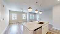 Located at 7551 Narcoossee Rd in Orlando, FL, this well-appointed single-story home offers three bedrooms, two bathrooms, and a thoughtfully designed layout across a comfortable footprint. The open-concept kitchen and living area serves as the heart of the home, featuring a large granite-topped island with an undermount sink, pendant lighting with brushed gold accents, white shaker cabinetry, a classic subway tile backsplash, and stainless steel appliances. The adjacent living room is bright and airy, with multiple windows, light-toned luxury vinyl plank flooring, and a ceiling fan overhead. A dedicated entrance and four closets provide excellent storage throughout. The spacious primary bedroom is carpeted for comfort and includes a walk-in closet and private access to a bathroom featuring a soaking tub framed by large-format neutral tiles and brushed nickel fixtures. The two additional bedrooms are also carpeted, naturally lit, and served by ceiling fans. A dedicated laundry room houses a full-size washer and dryer with built-in wire shelving. Neutral warm-toned walls, consistent flooring materials, and modern fixtures give the entire home a cohesive, contemporary feel.