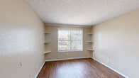 Located at 3241 Bonnie Dr in Fort Worth, TX, this one-bedroom, one-bathroom unit offers a practical and efficient single-floor layout. Wood-look flooring runs throughout the main living areas, lending warmth and continuity to the space. The open-concept living, dining, and kitchen area forms the heart of the unit, providing a versatile space for everyday living and entertaining. The kitchen is equipped with warm-toned cabinetry, a stainless steel refrigerator, a coil-top range, and a dishwasher, complemented by a tile backsplash and light granite-style countertops. The bedroom features built-in corner shelving flanking a window that allows natural light and outdoor views, along with additional closet space — with three closets total throughout the unit offering generous storage. A ceiling fan keeps the space comfortable. Neutral, warm beige tones on the walls are consistent throughout, creating a cohesive and calming ambiance. The bathroom includes a full tub-shower combination with white tile surround. Textured ceilings are present throughout the unit, adding a classic residential character to the overall design.