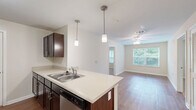 Located in Atlanta, GA, this 2-bedroom, 2-bathroom residence offers a practical and comfortable single-floor layout. The open-concept kitchen is a standout feature, boasting rich dark-espresso cabinetry, stainless steel appliances including a refrigerator, range, and microwave, and a peninsula counter with pendant lighting overhead — ideal for casual dining or entertaining. Warm wood-tone flooring runs throughout the kitchen and main living areas, creating a cohesive and inviting atmosphere.

Both bedrooms are carpeted for comfort, finished in neutral tones, and receive natural light through window treatments. The primary bedroom includes access to a dedicated walk-in closet outfitted with wire shelving systems, offering generous storage capacity. Each bathroom features a full tub-shower combination, wood-look flooring, and clean white fixtures with chrome hardware.

A utility room adds functional convenience, while the overall neutral color palette — soft beiges and whites accented by white trim and paneled doors — provides a clean, move-in-ready aesthetic. The efficient layout maximizes the use of the available floor space, making this residence a well-organized and comfortable home in the northwest Atlanta area.