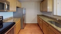 Located at 109 Hopkins St in Reading, Massachusetts, this single-floor residence offers a well-organized layout with consistent design elements throughout. The living area is a notable highlight, featuring warm hardwood-style flooring, recessed lighting, and a sliding glass door that opens to a private balcony overlooking a natural outdoor setting, allowing ample natural light to fill the space.

The kitchen is designed for functionality, featuring a galley-style layout with light maple cabinetry, granite countertops, and a full suite of stainless steel appliances, including a refrigerator, electric range, built-in microwave, and dishwasher. The hardwood-style flooring continues seamlessly from the living area into the kitchen.

The bedroom is a generously sized, open room with the same hardwood-style flooring, neutral wall tones, and closet storage. Two bathrooms serve the unit: one with a tiled floor, a vanity with storage, and a full tub-shower combination, and a second, more compact bathroom with tile flooring and a vanity. Panel-style doors are used consistently throughout, contributing to a clean, uniform aesthetic across the entire residence.