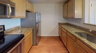 Located at 109 Hopkins St in Reading, Massachusetts, this single-floor residence offers a well-organized layout with consistent design elements throughout. The living area is a notable highlight, featuring warm hardwood-style flooring, recessed lighting, and a sliding glass door that opens to a private balcony overlooking a natural outdoor setting, allowing ample natural light to fill the space.

The kitchen is designed for functionality, featuring a galley-style layout with light maple cabinetry, granite countertops, and a full suite of stainless steel appliances, including a refrigerator, electric range, built-in microwave, and dishwasher. The hardwood-style flooring continues seamlessly from the living area into the kitchen.

The bedroom is a generously sized, open room with the same hardwood-style flooring, neutral wall tones, and closet storage. Two bathrooms serve the unit: one with a tiled floor, a vanity with storage, and a full tub-shower combination, and a second, more compact bathroom with tile flooring and a vanity. Panel-style doors are used consistently throughout, contributing to a clean, uniform aesthetic across the entire residence.