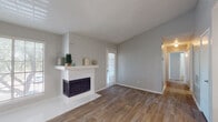 This single-story space offers a well-organized layout with a neutral color palette and a mix of flooring finishes that define each area. The entry opens into a bright living room finished with wood-look plank flooring and accented by a white-mantled fireplace, creating a welcoming focal point. Multiple windows fitted with blinds allow natural light to filter through, enhancing the open, airy feel of the space.

The kitchen is well-appointed with white shaker-style cabinetry, granite-look countertops, a white subway tile backsplash, and black appliances including a range, over-the-range microwave, and dishwasher. The clean, functional design provides ample counter and storage space.

Bedrooms are carpeted for comfort and each features windows that bring in natural light. One bedroom includes a ceiling fan with a light fixture and a wide bay-style window offering outdoor views, while another provides a quieter, more intimate setting.

Both bathrooms are finished consistently with white cabinetry, granite-look countertops, undermount sinks, dark-framed mirrors, and tub-shower combinations, reflecting a cohesive and updated aesthetic throughout. Textured ceilings are present across the space, adding subtle architectural character to each room.