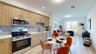Located at 7650 Van Nuys Blvd in Los Angeles, this well-designed one-bedroom, one-bathroom unit offers a thoughtfully efficient layout across a single floor. The open-concept living area seamlessly connects the kitchen, dining, and living spaces, creating an airy and cohesive environment filled with natural light from a large picture window that frames scenic mountain views.

The kitchen is outfitted with warm wood cabinetry, a grey tile backsplash, white quartz countertops, stainless steel appliances including a range, microwave, and dishwasher, and a matte black faucet — a clean blend of modern and natural aesthetics. Light wood-tone flooring runs throughout the main living areas, enhancing the bright, contemporary feel.

The living room is anchored by the large window overlooking the surrounding cityscape and mountains, providing a serene backdrop. The bedroom offers a comfortable, carpeted retreat with mirrored sliding closet doors, providing generous storage. The bathroom features large-format stone tile flooring, a floating wood vanity with white countertop, matte black fixtures, and a wide mirror, delivering a clean, modern finish. A hallway connects the private and shared spaces with ease, completing this efficiently designed urban residence.