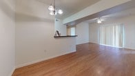 This single-floor residence offers a thoughtfully designed layout that blends comfort and functionality throughout. The open-concept living and dining area is a central highlight, featuring warm hardwood-style flooring, vaulted ceilings, and a ceiling fan that enhances airflow and light. A decorative chandelier illuminates the dining space, which connects seamlessly to the kitchen via a convenient pass-through bar counter with dark granite-style surfaces.

The kitchen is well-equipped with abundant warm oak cabinetry, dark countertops, a double-basin sink, and white appliances including a refrigerator, electric range, and over-the-range microwave. The hardwood-style flooring continues throughout this space, creating a cohesive feel.

The bedroom features plush wall-to-wall carpeting, a ceiling fan with light, and a generously sized window fitted with blinds that invite natural light while maintaining privacy.

Two full bathrooms serve the residence. One features a soaking tub and shower combination, a single-sink vanity with oak cabinetry, and tile flooring. The second bathroom mirrors this design with a tub/shower combo, matching cabinetry, and a light-toned countertop. Both bathrooms are practical and well-organized with ample storage overhead. The overall aesthetic is clean, neutral, and move-in ready.