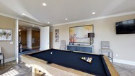 Located at 20 Ashton Village Dr in Westerville, Ohio, this single-floor residence offers a refined and well-appointed living environment. The space is highlighted by a sophisticated game room that serves as a standout feature of the home. This entertaining area is anchored by a full-size billiard table with a sleek black felt surface and natural wood frame, complemented by recessed lighting and elegant crown molding that runs along the ceiling perimeter. The neutral, warm-toned walls provide a refined backdrop, enhanced by curated wall art including a large-scale abstract painting and framed golf-themed prints that lend a personalized, leisure-oriented character to the room. A contemporary dark credenza with a stylish table lamp and accent seating complete the sophisticated look. The space flows naturally into adjacent areas of the home through a wide doorway, suggesting an open and connected floor plan. The combination of tasteful décor, quality finishes, and thoughtfully designed entertainment space makes this home well-suited for both relaxed everyday living and hosting guests. The overall ambiance is polished yet inviting, reflecting a careful attention to detail throughout.
