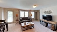 This single-floor residence offers a thoughtfully designed layout that balances comfort and functionality across its key living areas. The living room serves as the heart of the home, featuring plush carpeted flooring, large windows that invite generous natural light, and ample space for seating and entertainment. Adjacent to the living area, a dedicated dining space provides a natural gathering point for meals and conversation. The kitchen is well-equipped with warm medium-toned wood cabinetry, granite-style countertops, white appliances including a range, microwave, dishwasher, and a double basin sink — all arranged in a practical U-shaped configuration that maximizes workspace. Two carpeted bedrooms offer comfortable retreats, each with windows providing natural light and access to closet storage. One bedroom features corner windows, enhancing the sense of openness. The bathrooms are finished with tile flooring, wood vanity cabinetry, and tub-shower combinations. A utility area houses the electrical panel alongside laundry hookups, adding to the home's practical conveniences. Neutral tones throughout the interior create a warm and inviting ambiance well-suited for everyday living.