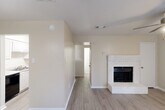 Located in Spring, TX, this two-story, 2-bedroom, 2-bathroom home offers a well-organized layout spread across two floors. The main level features a welcoming living room with wood-look plank flooring, a ceiling fan, and a classic white brick fireplace as the focal point. A large sliding glass door floods the space with natural light and provides a direct view of the entry area. The galley-style kitchen is outfitted with white cabinetry, light speckled countertops, a stainless steel sink, and black appliances, opening toward a bright dining area with hardwood-style flooring. A utility room and hallway round out the first floor. Upstairs, both bedrooms feature plush carpeting, ceiling fans, and vaulted ceilings that add a sense of openness. Each bedroom benefits from natural light through blinded windows. Two closets with wire shelving systems provide practical storage solutions. The upper floor also includes two full bathrooms and a hallway connecting all spaces. Neutral warm tones throughout create a clean and versatile aesthetic, making this home move-in ready. The overall layout is functional and efficient, ideal for comfortable everyday living.