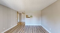 Located at 2001 Piner Road in Santa Rosa, California, this one-bedroom, one-bathroom residence offers a well-organized single-level layout across a compact yet functional floor plan. The living room features light-toned luxury vinyl plank flooring, neutral warm-gray walls, a textured ceiling, and a ceiling fan, creating a bright and comfortable gathering space. A pass-through window connects the living and dining area to the kitchen, enhancing the open feel between rooms. The combined dining area and kitchen is thoughtfully designed with white shaker-style cabinetry, stone-toned countertops, and stainless steel appliances including a dishwasher, electric range, and refrigerator, all set on matching LVP flooring. The living room also includes a sliding glass door that opens to a private balcony, allowing natural light and outdoor access. The bedroom is carpeted for comfort and includes a window with blinds that brings in natural light, along with a baseboard heater for warmth. The bathroom is fitted with a full tub/shower combination and LVP flooring. Additional conveniences include an in-unit laundry area and a dedicated closet, rounding out this practical and move-in-ready residence.
