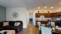 This single-floor residence is thoughtfully designed with an open-concept layout that seamlessly connects the living, dining, and kitchen areas. Rich wood-look flooring flows throughout the main living spaces, lending warmth and continuity to the design. The kitchen is well-equipped with rich dark-stained cabinetry extending to the ceiling, granite-style countertops, a stainless steel appliance suite including a refrigerator, range, microwave, and dishwasher, and a deep undermount sink. A dedicated dining area adjacent to the kitchen provides ample space for entertaining. The living room features a teal accent wall and large windows that invite natural light.

The residence includes multiple bedrooms, each carpeted for comfort. One bedroom showcases a bold mauve accent wall, while another benefits from corner windows with outdoor views. Two bathrooms are finished with dark wood vanities, white countertops, and wood-look tile flooring. One bathroom offers a generous vanity with built-in shelving and additional storage cabinetry, while the second includes a window for natural light and a shower-tub combination. A hallway with multiple closet doors provides practical storage throughout.