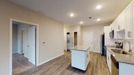 Located at 403 Pearl St in Jeffersonville, Indiana, this single-floor residence offers a thoughtfully designed layout with modern finishes throughout. The open-concept kitchen serves as the heart of the space, showcasing crisp white shaker cabinetry, granite countertops, a central island for additional prep and seating space, and a full suite of stainless steel appliances including a range, microwave, dishwasher, and refrigerator. Recessed lighting illuminates the kitchen and living area, which flows seamlessly across durable wood-look flooring. The bedroom features plush carpeting underfoot and a generously sized window that invites natural light into the room, creating a comfortable and airy atmosphere. The bathroom is well-appointed with a tiled tub-shower surround, granite-topped vanity with white cabinetry, and coordinating wood-look flooring. Additional practical features include an in-unit laundry area and ample storage space. The neutral color palette and clean architectural lines throughout the unit give it a fresh, contemporary feel, making it a functional and attractive living space in the Jeffersonville community.