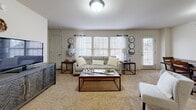 This 2-bedroom, 3-bathroom single-floor residence in Tulsa, Oklahoma offers a well-organized layout designed for comfortable everyday living. The open-concept living and dining area is carpeted and filled with natural light from multiple windows dressed with white blinds and sheer curtains. The space flows seamlessly into the kitchen, which is separated by a breakfast bar with seating. The kitchen is fully equipped with rich dark wood cabinetry, granite-style countertops, stainless steel appliances including a refrigerator, range, microwave, and dishwasher, and tile flooring. The primary bedroom is a well-proportioned retreat featuring plush carpet, a ceiling fan, a walk-in closet, and a private en-suite bathroom with a granite-topped vanity, dark wood cabinetry, and a tub-shower combo. The second bedroom is similarly appointed with carpet, a ceiling fan, and a window for natural light. Three bathrooms throughout the residence provide ample convenience. Two dedicated closets offer practical storage solutions. A connecting hallway ties the layout together efficiently. The neutral color palette, consistent use of dark wood accents, and tile flooring in wet areas contribute to a cohesive and functional aesthetic throughout.