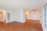 Located at 2420 Pacific Dr in Santa Clara, CA, this two-bedroom, one-bathroom residence offers a well-organized single-floor layout designed for comfortable everyday living. The living room serves as the heart of the home, featuring warm hardwood-style flooring, a textured ceiling, and large sliding windows that invite generous natural light and peaceful views of the surrounding mature trees and greenery. A wall-mounted AC unit provides climate control convenience. The kitchen is thoughtfully designed with white cabinetry extending to the ceiling, white appliances including a refrigerator, dishwasher, and electric range, light wood-style flooring, and ample counter space — all under flush ceiling lighting. The two bedrooms offer a quiet retreat, with the primary bedroom providing a spacious layout with plush carpeting and clean white walls. The full bathroom is finished with wood-style flooring, a combined tub and shower enclosed by sliding frosted glass doors, a vanity, and a toilet. A hallway connects the rooms efficiently. The private balcony, accessible from the living area, overlooks a lush canopy of tall cypress and deciduous trees, offering a serene outdoor escape in the heart of Silicon Valley.