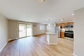 Located in La Fayette, NY, this 2-bedroom, 1-bathroom residence offers a thoughtfully designed single-floor layout that maximizes comfort and functionality. The open-concept living and kitchen area serves as the heart of the home, featuring light hardwood flooring that flows seamlessly throughout. The kitchen is well-equipped with warm-toned wooden cabinetry, granite countertops, a central island with additional granite surface space, and a full suite of stainless steel appliances including a refrigerator, range, microwave, and dishwasher. A pendant light fixture adds a polished finishing touch above the island. The living area is bright and airy, bathed in natural light from dual windows and a sliding glass door that opens to an outdoor balcony, offering pleasant outdoor views. Baseboard heating runs along the perimeter of the living space for year-round comfort. Both bedrooms are carpeted and feature neutral tones, with the primary bedroom offering generous proportions and a closet. Additional storage is abundant, with five closets distributed throughout the unit. The full bathroom includes a tub-shower combination, a wooden vanity with a granite countertop, and clean white finishes throughout.