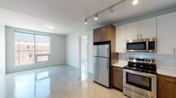 This well-designed two-bedroom, two-bathroom residence offers a thoughtfully laid-out single-floor plan that maximizes functionality and style. The open-concept kitchen is a standout feature, equipped with stainless steel appliances including a refrigerator, electric range, built-in microwave, and dishwasher. Cabinetry combines white upper cabinets with warm wood-toned lower cabinets, complemented by a clean white quartz countertop and a classic subway tile backsplash. Track lighting overhead enhances the modern aesthetic throughout the kitchen and living area. Polished concrete-style floors run through the main living spaces, reflecting natural light that filters in through generous windows. The bedrooms are comfortable and well-proportioned, each featuring ceiling fans and neutral tones, with one bedroom enjoying direct access to natural light through a large window. The bathrooms are finished with elegant large-format marble-look tiles surrounding the soaking tub and shower combination, paired with wood-toned vanities and white countertops. The overall ambiance is clean, contemporary, and move-in ready, with a cohesive design language that blends modern finishes with functional living spaces throughout.