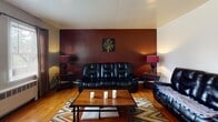This single-floor residence offers a thoughtfully arranged layout that balances comfort and functionality across its key living spaces. Warm hardwood floors run throughout, lending a consistent and inviting character to every room.

The living room makes a strong first impression with a bold, deep-red accent wall that anchors the space, complemented by neutral surrounding walls and hardwood flooring underfoot. The dining area, situated adjacent to the kitchen, is bright and well-lit thanks to multiple windows dressed with floor-length curtains, and features a ceiling fan that adds to the room's airy feel.

The kitchen is equipped with honey-toned wood cabinetry — both upper and lower — paired with dark granite-style countertops, a stainless steel sink, and a full-size refrigerator, offering ample storage and prep space.

Two bedrooms provide comfortable accommodations. The primary bedroom features hardwood floors, a ceiling fan, and windows that allow natural light to fill the room. The second bedroom also showcases hardwood floors and two windows adorned with vibrant teal curtains, adding a lively touch, and includes a bunk bed setup that maximizes the use of space.

The bathroom reflects a classic design with white subway tile walls accented by dark trim, a tiled floor, a vanity with wood cabinetry, and a shower-tub combination.