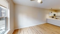 Located at 900 3rd St SE in Cedar Rapids, Iowa, this one-bedroom unit offers a well-designed single-floor layout with a clean, modern aesthetic. The open-concept kitchen and living area serves as the heart of the space, featuring crisp white shaker-style cabinetry extending to the ceiling, white quartz countertops, and a full suite of stainless steel appliances including a range, over-the-range microwave, dishwasher, and French door refrigerator. Stylish pendant lights hang above the kitchen, adding a warm, contemporary touch. Light wood-tone flooring runs throughout the main living area, enhancing the bright and airy feel of the space. The bedroom is a comfortable, well-proportioned retreat finished with plush carpet, warm neutral-toned walls, and a ceiling fan. A window brings in natural light and offers views of the surrounding Cedar Rapids neighborhood. The bedroom also includes a closet and connects conveniently to the rest of the unit. The overall design throughout emphasizes clean lines, neutral tones, and modern finishes, creating a cohesive and functional living environment suited for everyday comfort.