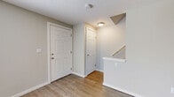 Located at 1541 Barnes Drive East in Columbus, Ohio, this multi-floor home offers two bedrooms, one bathroom, and a thoughtfully laid-out floor plan spread across three levels. The entry level welcomes you with light hardwood-style flooring, neutral-toned walls, and a staircase providing easy access to the upper and lower floors. The main living area is bright and open, featuring large windows with blinds that allow natural light to fill the space. The kitchen is well-appointed with white cabinetry, granite-style countertops, and black appliances including a refrigerator, range, built-in microwave, and dishwasher — all set atop matching hardwood-style floors. Both bedrooms are carpeted and offer comfortable proportions; the primary bedroom includes a generous double closet with sliding doors and built-in shelving. The full bathroom features a tub-shower combination, a single vanity with a vessel sink, and hardwood-style flooring. The lower level provides additional living space with vinyl flooring and painted cinder block walls, suitable for use as a recreation room, home office, or utility area. A utility room and dedicated hallway and closet complete the practical layout of this functional and well-maintained home.