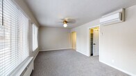 Located at 225 S 400 E in Salt Lake City, Utah, this single-floor unit blends classic architectural charm with modern updates throughout. The main living area is generously sized, featuring soft neutral-toned carpet, a textured ceiling, a brass ceiling light fixture, and multiple windows with white blinds that invite natural light. A charming arched doorway connects the living space to additional rooms, adding a timeless architectural detail. A wall-mounted mini-split air conditioning unit ensures year-round climate comfort.

The kitchen has been thoughtfully renovated, showcasing dark navy cabinetry with gold hardware, granite-patterned countertops, a white subway tile backsplash, and stainless steel appliances including a range, microwave, and dishwasher. A gold-tone faucet over a single-basin sink completes the polished look, complemented by light hardwood-style flooring.

The bedroom is spacious and carpeted, offering ample room and access to a dedicated walk-in closet with built-in shelving. An additional room provides flexible use with carpet flooring and natural light from a window overlooking the outdoors.

The bathroom is elegantly appointed with white subway tile walls, marble-look tile flooring, a pedestal sink, gold fixtures, an illuminated vanity mirror, and a soaking tub with a shower — creating a clean, spa-like atmosphere.