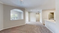 This single-story, 1-bedroom, 2-bathroom residence offers a thoughtfully designed layout that maximizes comfort and functionality. The combined kitchen and living area serves as the heart of the home, featuring plush carpeting, crown molding, and elegant arched architectural details that add character to the open space. Recessed lighting and a pendant light fixture provide warm, layered illumination throughout.

The kitchen is well-equipped with stainless steel appliances, including a range, microwave, and dishwasher. Gray lower cabinetry is paired with white upper cabinets and crisp white countertops, all set atop rich hardwood-style flooring that extends through the kitchen and hallways.

The bedroom is a comfortable retreat, carpeted for warmth and featuring a ceiling fan, natural light from a large window with outdoor views, and access to a generous walk-in closet outfitted with wire shelving systems for organized storage.

Both bathrooms are finished with gray vanity cabinetry, white countertops, and well-lit mirrors. The dedicated laundry room includes side-by-side washer and dryer units with additional wire shelving overhead for extra storage.

A welcoming entrance and connecting hallway complete the layout, creating a cohesive, move-in-ready living space with neutral tones throughout.