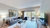 Located at 1155 Museum Blvd in Vernon Hills, IL, this well-appointed two-bedroom, one-bathroom residence offers a thoughtfully designed open-concept layout across a single floor. Light wood-style flooring flows throughout the main living areas, lending a clean, cohesive aesthetic.

The kitchen is a standout feature, showcasing white cabinetry, a tile backsplash, stainless steel appliances including a gas range, microwave, and refrigerator, and a white quartz peninsula with bar seating — ideal for casual dining or entertaining. Track lighting illuminates the space efficiently. The adjacent dining area benefits from a stylish pendant light fixture, and the combined layout creates a seamless flow into the spacious living room, which is filled with natural light from large sliding glass doors that open onto a private balcony with tree-lined views.

The primary bedroom offers comfortable proportions and connects to a custom walk-in closet with built-in shelving, hanging rods, and drawers. The full bathroom features a tub-shower combination, a white vanity with a stone-topped countertop, and wood-style flooring. Additional highlights include five total closets, a dedicated pantry, a laundry area, and a utility room, providing exceptional storage throughout.