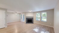 This two-story, two-bedroom, three-bathroom home in Tualatin, Oregon offers a well-organized layout spread across two floors. The main level opens into a spacious living area featuring light wood-style flooring, neutral-toned walls, a ceiling fan, and a tile-surround fireplace as a central focal point. Natural light pours in through multiple windows fitted with blinds, offering pleasant views of surrounding greenery. A door leads directly outdoors from the living area. The kitchen is well-appointed with rich dark lower cabinetry, white upper cabinets, stainless steel appliances, a subway tile backsplash, white countertops, and a deep undermount sink beneath a bright window. The upper floor houses the bedrooms, including a generously sized primary bedroom with hardwood-style flooring and dual windows that let in ample natural light. The three bathrooms are clean and functional, with one featuring a soaking tub and modern vanity, and another offering a tub-shower combination accented by small windows above. A hallway connects the upper-floor rooms efficiently, with a closet providing additional storage. The home's consistent use of light flooring, neutral paint tones, and modern fixtures creates a cohesive, bright, and welcoming atmosphere throughout.