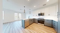 Located at 505 West Eighth Street in Dallas, TX, this well-designed one-bedroom, one-bathroom residence offers a thoughtfully planned single-floor layout that maximizes functionality and style. The open-concept living, dining, and kitchen area serves as the heart of the home, featuring light hardwood-style flooring, white walls, and abundant natural light streaming through large windows and French doors. A ceiling fan adds to the comfort of the living space, which opens directly onto a private patio.

The kitchen is a standout feature, showcasing a two-tone design with crisp white upper cabinets and sage-gray lower cabinets, a herringbone tile backsplash, and a suite of stainless steel appliances including a range, microwave, dishwasher, and French door refrigerator. Sleek pendant lighting hangs above the peninsula, which includes an undermount sink.

The bedroom is generously proportioned, outfitted with plush carpet, a bank of three large windows with outdoor views, and access to two closets. The full bathroom is finished in a clean, modern aesthetic with white subway-style tile surrounding the tub and shower, matte black fixtures, a single-sink vanity with quartz countertop, and marble-look tile flooring.