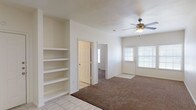 Located at 9257 Somerset Rd in San Antonio, TX, this two-story home offers a practical and comfortable layout spread across two levels. The main living area on the ground floor features warm neutral tones, plush carpeting, a ceiling fan, and built-in shelving — ideal for storage and display. Natural light filters in through blinded windows, creating a bright and welcoming atmosphere.

The kitchen is well-appointed with warm oak cabinetry, dark countertops, tile flooring, a double-basin sink, a dishwasher, an electric range, and a built-in microwave. A carpeted staircase connects the two floors, with the kitchen and main living spaces conveniently situated on the ground level.

The bedrooms are carpeted and generously sized, each equipped with ceiling fans. The primary bedroom features elevated ceilings and an en-suite bathroom with a wood-vanity, large mirror, and tile flooring. Additional bedrooms include double-door closets, offering ample storage. A secondary bathroom mirrors the same clean, functional design with a vanity, overhead mirror, wall-mounted cabinet, and tiled floors.

The home also includes an attached single-car garage with a roll-up door, providing secure parking and additional storage space. Throughout the home, the consistent use of neutral colors and durable materials creates a cohesive and move-in-ready environment.