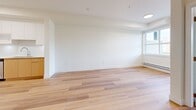Located at 11779 Burnett St in Maple Ridge, BC, this thoughtfully designed one-bedroom, one-bathroom unit offers a clean, modern aesthetic across a single floor. Light-toned hardwood flooring flows throughout, creating a bright and cohesive feel that ties each area together seamlessly.

The open-concept kitchen and living area forms the heart of the unit. The kitchen is well-appointed with white upper cabinetry, warm wood-toned lower cabinets, a white tile backsplash, stainless steel appliances including a refrigerator, dishwasher, and range, and recessed under-cabinet lighting. The generous open living area offers ample natural light from a large window, with a door providing access to an outdoor space featuring views of surrounding greenery.

The bedroom is a comfortable, well-proportioned room with a large window that frames peaceful outdoor views of trees and the surrounding landscape. A baseboard heating system is present throughout the unit. Two closets offer practical storage solutions.

The bathroom maintains the unit's clean, modern palette with all-white finishes, large-format marble-effect floor tiles, a full soaker tub with tiled surround, a vanity with storage, and crisp white walls. The overall ambiance of the unit is fresh, minimal, and move-in ready.