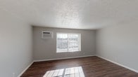 Located at 1040 Cross Keys Rd in Lexington, Kentucky, this single-floor unit offers a straightforward, functional layout across several rooms, all unified by rich, dark hardwood-style flooring and neutral gray wall tones throughout. The living areas are bright and open, benefiting from multiple windows fitted with blinds that allow natural light to filter in and illuminate the floors. Textured ceilings add a classic finish to each room.

The kitchen is equipped with gray cabinetry offering ample upper and lower storage, light-toned laminate countertops, a double stainless steel sink, and black appliances including a refrigerator and range. The full bathroom features a single-sink vanity with a granite-style countertop, a large mirror, a toilet, and a bathtub/shower combination, all finished with consistent hardwood-style flooring.

Multiple rooms throughout the unit provide flexible space suitable for bedrooms or living areas. Several of these rooms are equipped with wall-mounted HVAC units and windows that bring in natural light. The overall design is clean, neutral, and practical, creating a move-in ready environment well-suited for comfortable everyday living in the Lexington area.