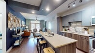 Located at 290 M.L.K. Jr Dr SE in Atlanta, Georgia, this single-floor residence offers a thoughtfully designed open-concept layout with contemporary finishes throughout. The kitchen serves as a central highlight, featuring two-tone cabinetry in slate gray and warm wood tones, a tiled backsplash, stainless steel appliances including a refrigerator, range, microwave, and dishwasher, and a generous island with a quartz countertop and bar seating — ideal for casual dining or entertaining. Track lighting above the kitchen's tray ceiling adds a polished, modern touch. The living area flows seamlessly from the kitchen and is anchored by a bold navy accent wall, wood-style flooring, and a ceiling fan. Large windows allow abundant natural light and offer views of the surrounding greenery. The bedrooms are carpeted and serene, with ceiling fans, well-sized windows, and walk-in closets equipped with wire shelving for organized storage. The bathroom is finished with large-format tile flooring, a wood-toned vanity with quartz countertop, a framed mirror, and a glass-enclosed shower. The overall design balances modern urban aesthetics with comfortable, functional living in the heart of Atlanta.