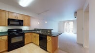Located at 2751 Shadow View Dr in Eugene, Oregon, this single-floor unit offers a well-organized, open-concept layout designed for comfortable everyday living. The kitchen serves as a central feature, outfitted with warm maple cabinetry, dark granite countertops, and a full suite of black appliances including a range, built-in microwave, refrigerator, and dishwasher. Light hardwood-style flooring runs throughout the kitchen area, while pendant lighting and a track lighting system provide targeted illumination. A peninsula counter with an extended bar top creates a natural transition into the adjoining living area, which is finished with neutral carpet and benefits from abundant natural light through a large sliding glass door fitted with vertical blinds. The sliding door leads to an outdoor space, offering a pleasant connection to the exterior. A bedroom features carpet flooring, a window with outdoor views, and a distinctive two-tone accent wall. The bathroom includes a wood vanity with granite countertop, a tub-shower combination, and is conveniently situated adjacent to an in-unit stacked washer and dryer. Throughout the space, the clean, neutral palette and functional design elements contribute to a calm, move-in-ready atmosphere.