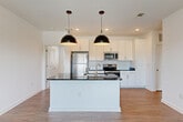 Located at 5740 Buffington Rd in Union City, GA, this single-story, 3-bedroom, 2-bathroom home offers a well-designed open-concept layout with modern finishes throughout. The kitchen serves as the heart of the home, featuring crisp white shaker cabinetry that extends to the ceiling, a classic white subway tile backsplash, dark granite countertops, and a full suite of stainless steel appliances including a refrigerator, electric range, and built-in microwave. A large center island with a sink and pendant lighting provides additional prep space and casual seating, flowing seamlessly into the living area. Warm wood-look flooring runs throughout the main living spaces, adding continuity and a clean aesthetic. The bedrooms offer a comfortable retreat, with plush carpet flooring and ceiling fans in select rooms. Natural light enters through blinds-equipped windows, with outdoor views of the surrounding neighborhood. The two bathrooms are consistently appointed with white cabinetry, dark granite vanity tops, and combination tub-shower units. Four closets throughout the home ensure ample storage. The clean, neutral palette and modern fixtures create a bright, move-in-ready environment well-suited for comfortable everyday living.