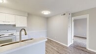 This well-designed one-bedroom, one-bathroom unit offers a practical and efficient single-floor layout. The combined kitchen and living area forms the heart of the space, with the living room featuring wood-look laminate flooring, a ceiling fan with lighting, and a sliding glass door that opens to a private balcony, allowing natural light to fill the room. A second window further enhances the brightness of the living area.

The galley-style kitchen is efficiently organized with white cabinetry lining both walls, offering ample storage. White appliances, including a range and refrigerator, are complemented by a stainless steel double sink with a brushed gold faucet and light-toned countertops. A textured ceiling is consistent throughout the unit.

The bedroom is carpeted for comfort and features two separate closets, providing generous storage. A window with blinds allows natural light in, and a sliding glass door offers direct balcony access.

The bathroom includes a white vanity with a quartz-style countertop, an integrated sink, a large mirror, and a tiled shower-tub combination, finished with wood-look flooring for a cohesive aesthetic.