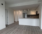 Located at 14585 104 Ave in Surrey, BC, this modern 1-bedroom, 2-bathroom condominium spans 600 square feet of well-appointed single-floor living. The open-concept layout seamlessly connects the kitchen, dining, and living areas, all finished with wide-plank grey laminate flooring that flows throughout the unit. The contemporary kitchen features white flat-panel cabinetry, a taupe tile backsplash, stainless steel appliances including a French door refrigerator and built-in microwave, and a central island with an undermount sink and integrated dishwasher — ideal for both cooking and entertaining. The living room is bright and airy, with large floor-to-ceiling sliding glass doors providing access to a balcony and filling the space with natural light and green outdoor views. The primary bedroom measures 130 square feet and includes a built-in closet with shelving and a large window overlooking the surrounding neighbourhood and tree canopy. Both bathrooms are finished with stone-look quartz countertops, undermount sinks, and warm wood-toned cabinetry. The unit's clean white walls and modern hardware contribute to a cohesive, contemporary aesthetic throughout.