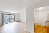 This single-floor unit offers a clean, modern layout with two bedrooms, two bathrooms, and a thoughtfully organized floor plan. The open living area is bright and airy, finished with light wood flooring throughout that lends warmth and visual continuity across the space. A large sliding glass door leads to a balcony, filling the living room with natural light and providing outdoor views of the surrounding building exterior.

The kitchen is positioned adjacent to the living area, separated by a partial wall that defines each zone while maintaining an open feel. It features white cabinetry, light countertops, and stainless steel appliances, including a full-size refrigerator, arranged in a galley-style configuration that maximizes efficiency.

The primary bedroom is a well-proportioned room with a dedicated walk-in closet equipped with built-in shelving and hanging rods. The second bedroom also benefits from its own walk-in closet with similar built-in storage. Both rooms feature the same light wood flooring found throughout the unit, and natural light enters through windows overlooking the exterior.

Each of the two bathrooms is finished with clean, neutral tones. The bathrooms include a full tub-shower combination with brushed nickel fixtures, a white vanity with a solid countertop, and tile flooring, offering a functional and cohesive aesthetic throughout.