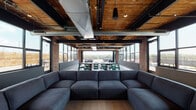 Located at 230 East Ave in Norwalk, CT, this single-floor space showcases a striking industrial-modern aesthetic that seamlessly blends raw architectural elements with refined interior design. Exposed brick columns, dark structural steel beams, and warm wood-plank ceilings set a distinctive tone throughout, while visible ductwork adds to the authentic loft-style character.

The open-plan layout is anchored by generous lounge seating, including a large sectional sofa and tufted Chesterfield couches, complemented by velvet accent chairs and layered area rugs in rich teal tones. A communal high-top table with green metal stools provides a casual gathering and dining area. The polished concrete and light hardwood flooring ground the space with a clean, contemporary finish.

Floor-to-ceiling windows wrap the perimeter, flooding the interior with abundant natural light and offering sweeping rooftop views of the surrounding Norwalk skyline. Expansive folding glass doors open directly onto an outdoor terrace, which features additional seating, a pool, and al fresco dining areas — creating a seamless indoor-outdoor flow.

The space is well-suited for events, social gatherings, or collaborative use, with its versatile layout and distinctive architectural character making it a standout venue in the South Norwalk area.