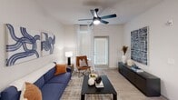 This contemporary 650 square foot apartment offers a thoughtfully designed living space in Nashville, TN. The open-concept floor plan seamlessly integrates the living room, dining area, and kitchen, creating a spacious feel despite the compact footprint. The living room features a comfortable blue sofa, modern artwork, and a ceiling fan for comfort. Large windows with sheer curtains allow ample natural light, enhancing the airy ambiance.

The kitchen boasts sleek white cabinetry, stainless steel appliances, and a convenient island with seating. Adjacent to the kitchen, a round dining table with blue chairs provides a cozy spot for meals. The bedroom, measuring 180 square feet, includes a queen-sized bed, stylish bedside tables, and an en-suite bathroom. The bathroom features a tub/shower combination with white tiled walls.

Throughout the apartment, a neutral color palette with pops of blue and orange creates a cohesive, contemporary aesthetic. Light wood-look flooring in the main living areas contrasts with plush carpeting in the bedroom. The unit also includes in-unit laundry facilities, adding convenience to this well-appointed urban dwelling.
