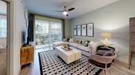 This single-floor residence offers a thoughtfully designed open-concept layout that seamlessly connects the kitchen, dining, and living areas. The kitchen is a standout feature, showcasing white cabinetry, granite countertops with a subway tile backsplash, stainless steel appliances, and a central island with bar seating — ideal for both casual dining and entertaining. Light wood-style flooring flows throughout the main living areas, enhancing the bright and airy feel of the space. The living room is generously sized and opens directly to a private balcony through sliding glass doors, bringing in abundant natural light and outdoor views. A ceiling fan adds comfort to the space. In-unit stacked washer and dryer provide everyday convenience. The primary bedroom is a serene retreat with plush carpet, a ceiling fan, and a bold accent wall adorned with decorative wall-mounted planters. It connects directly to a well-appointed en-suite bathroom featuring granite countertops, white cabinetry, tile flooring, and access to a walk-in closet. The second bedroom is equally inviting, with carpet flooring, a large window overlooking greenery, and ample natural light. Every detail of this residence reflects a clean, contemporary aesthetic with functional design throughout.